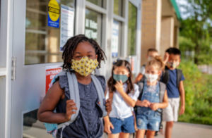 group of elementary school kids go back to school wearing masks