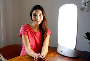 Smiling woman sitting in front of her full-spectrum light