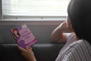 Woman pauses to look outside while reading So I Was Thinking About Adoption