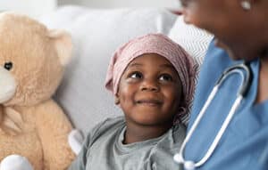 Smiling boy with cancer comforted by female doctor