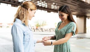 An adoptive mother putting adoption symbol jewelry on her son's birth mother's wrist